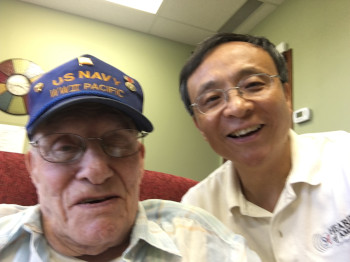 Dr. Jerry Zhou poses for a photo in his office with a US Navy World War II veteran